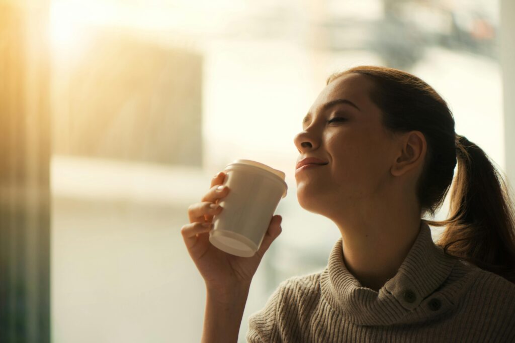 A woman sitting quietly with a cup of coffee in soft natural light.